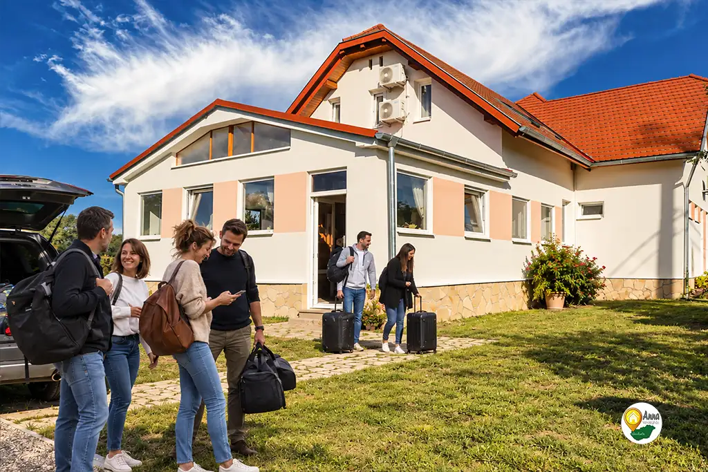 Kisebb c&eacute;ges csapat &eacute;rkezik csomagokkal az Anna Vend&eacute;gh&aacute;zhoz Szelest&eacute;n. A k&eacute;p a k&ouml;z&ouml;s sz&aacute;ll&aacute;s, a csapat&eacute;p&iacute;tő program &eacute;s az egy helyen t&ouml;rt&eacute;nő elhelyez&eacute;s hangulat&aacute;t mutatja be.